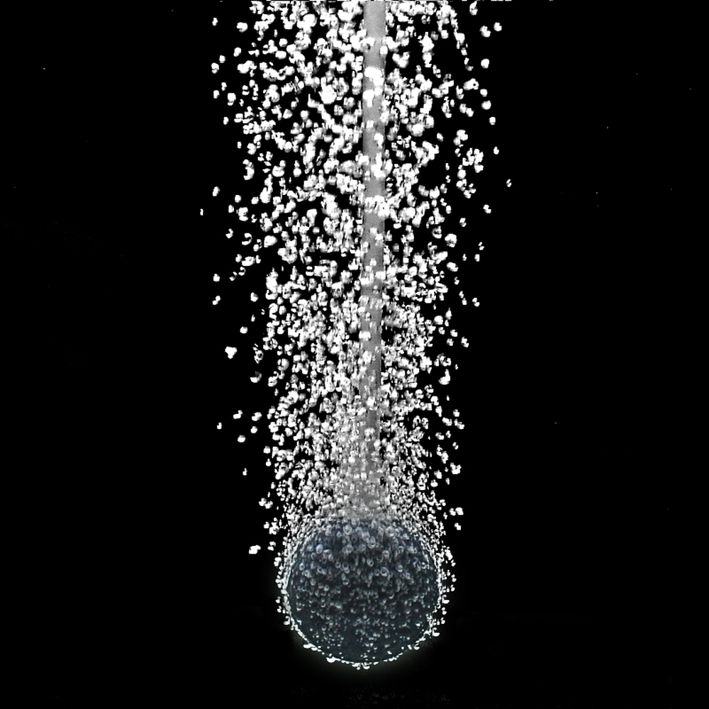 Spherical aquarium air stone producing a rising stream of bubbles underwater against a black background.