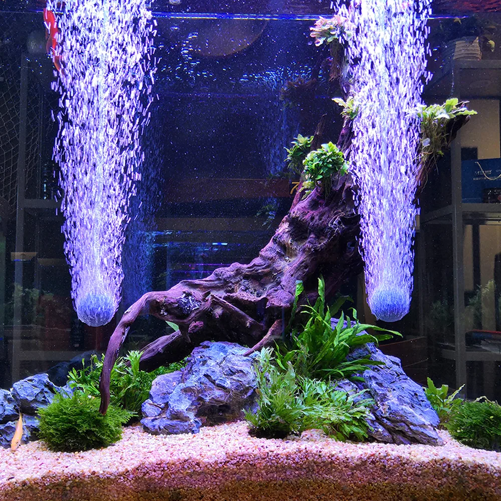 Two spherical aquarium air stones producing columns of bubbles in a planted aquarium with driftwood and rocks.