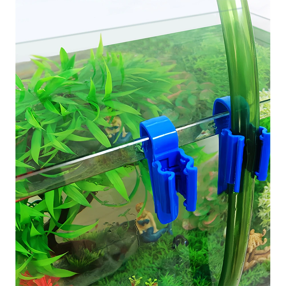 Two blue aquarium hose holder clips on a glass tank rim, one holding a green hose.