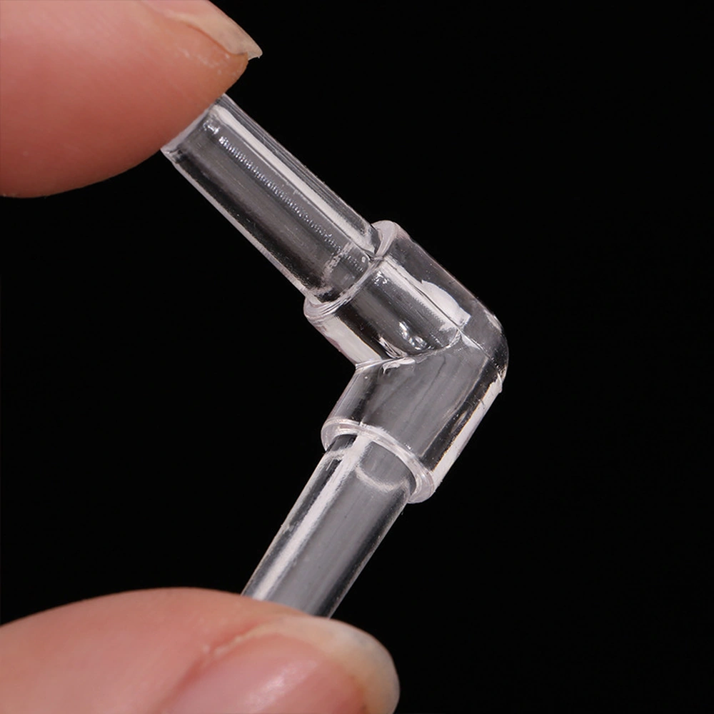 Clear aquarium airline elbow connector held between fingertips, showing the 90° bend and stepped connection ends.